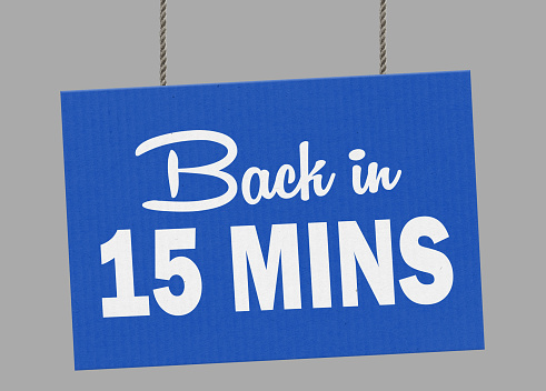 cardboard-back-in-15-minutes-sign-hanging-from-ropes-clipping-path-picture-id1047121856