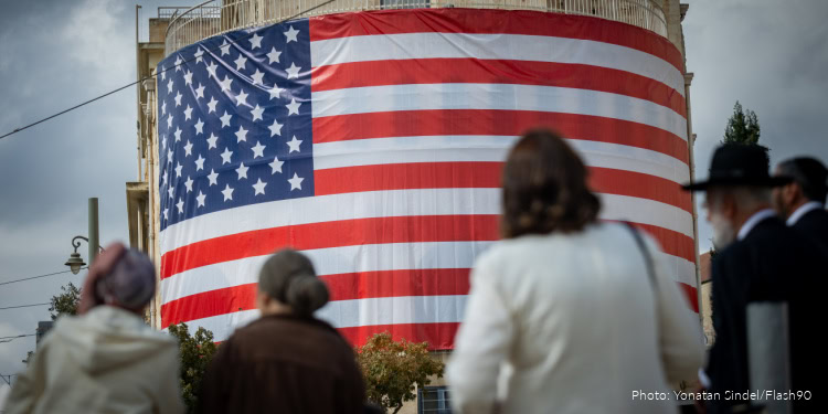 People walking next to a large American flag at the Tsahal Square in Jerusalem, in honor of U.S. President Donald Trump, October 12, 2025