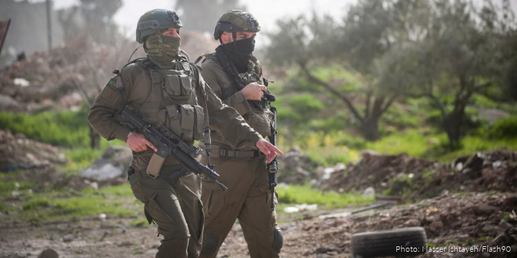 Two armed security personnel in tactical gear patrolling a rural area, providing safety and support in conflict zones.