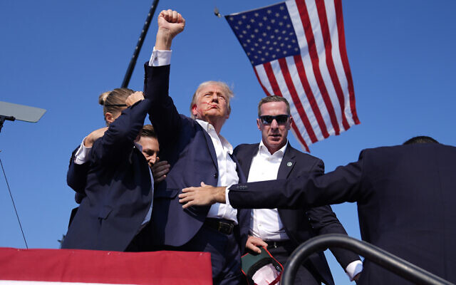 Republican presidential candidate former President Donald Trump gestures as he is surrounded by US Secret Service agents as he leaves the stage at a campaign rally after an assassination attrempt, July 13, 2024, in Butler, Pennsylvania. (AP Photo/Evan Vucci)