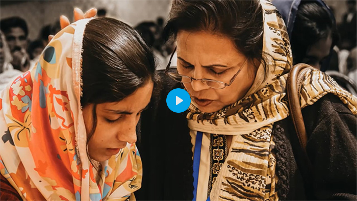 Video preview - The screenshot shows two women praying together. A video play button indicates that this is a link to the video.