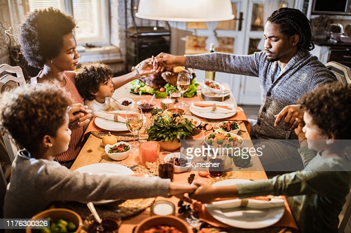 religious-black-family-saying-grace-before-thanksgiving-lunch-at-home-picture-id1176300326