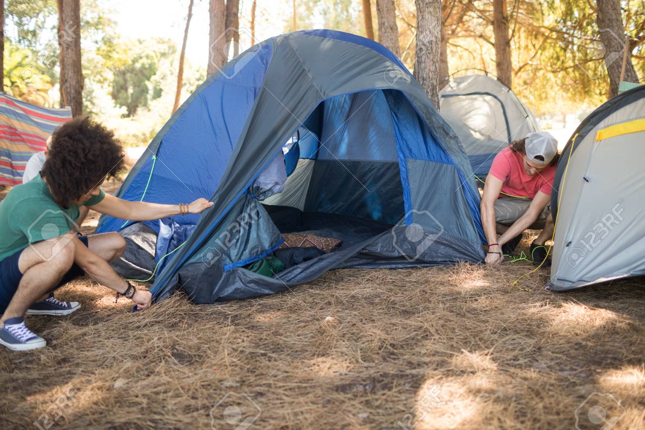 82480759-male-friends-making-tent-on-field-during-camping.jpg